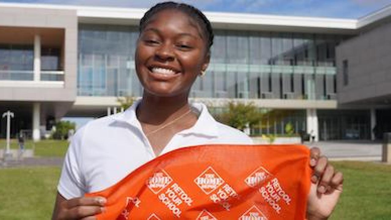 Female Black student at an HBCU holding a Retool your School banner.