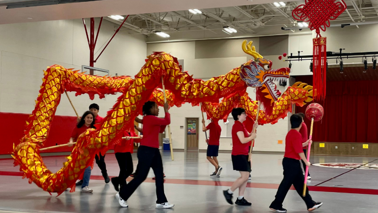 Group of students wearing red performing traditional dragon dance