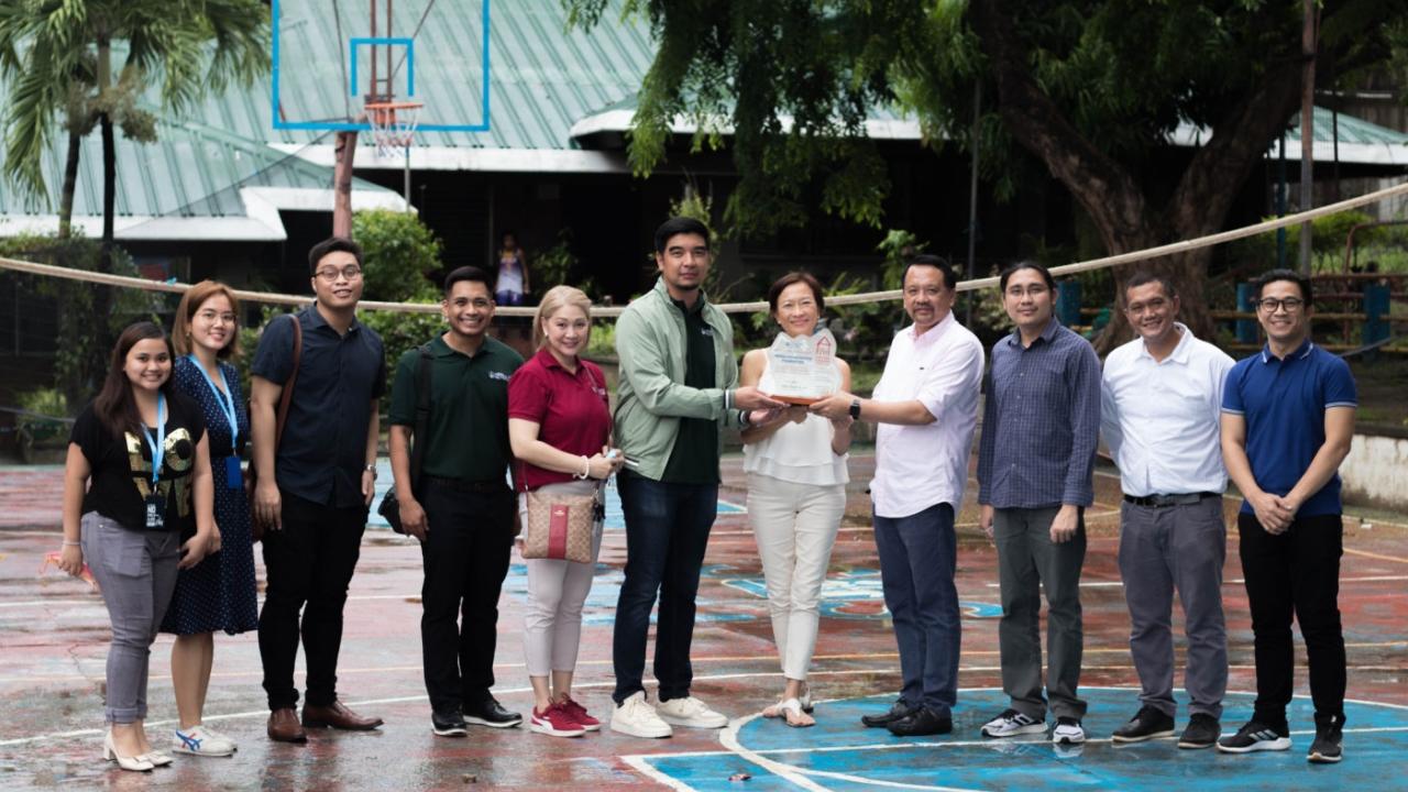 a group of people on a basketball court, three holding an award
