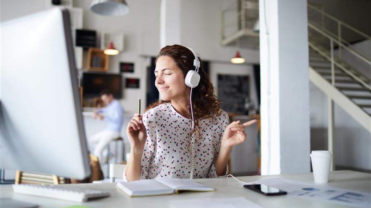 A woman seated at her desk with headphones on.