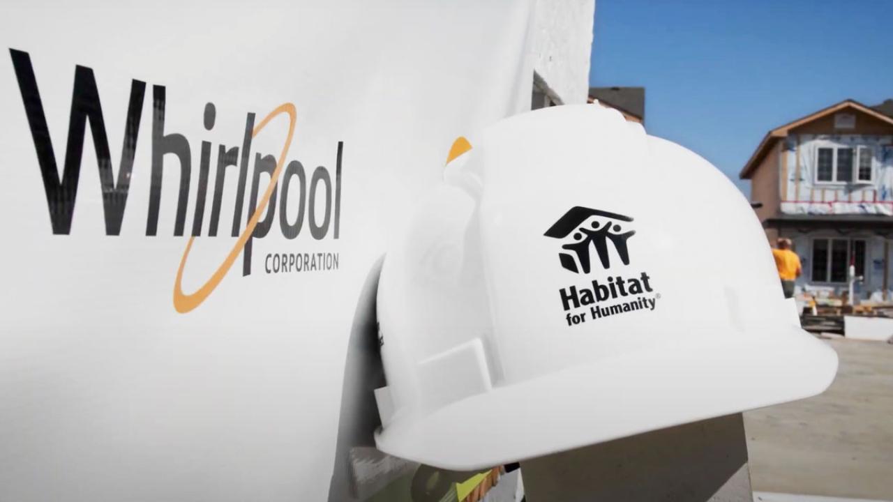 hard hat with habitat for humanity logo next to a whirlpool logo on a vehicle