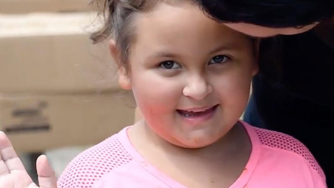 Young girl smiling and waving.