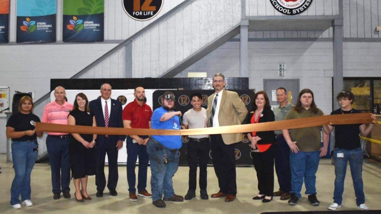 A group of people stood behind a ribbon inside a hall
