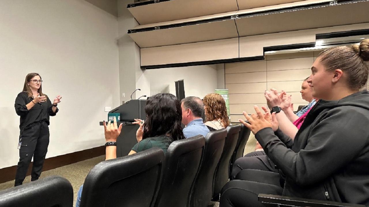 Moratz (left) teaching the sign for basketball during an ASL class at the DICK’S Sporting Goods Customer Support Center
