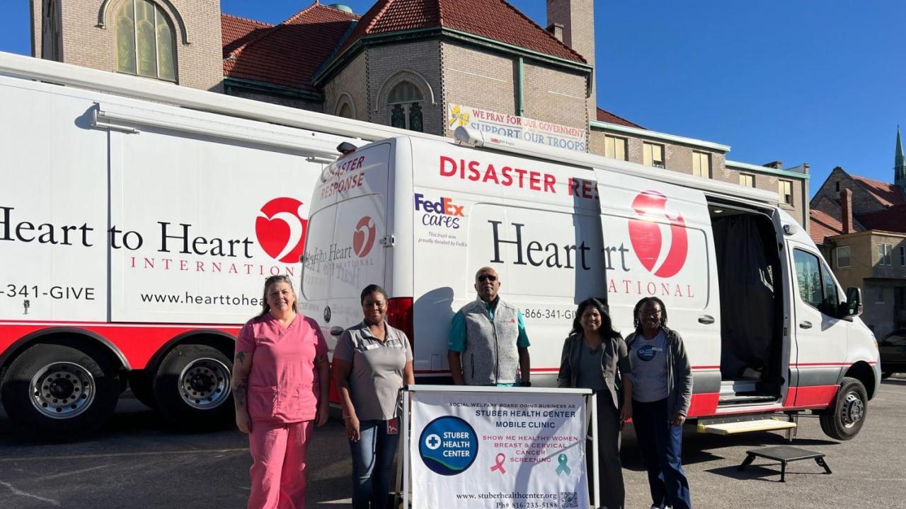Group photo in front of Heart to Heart van and truck
