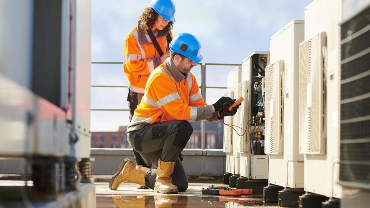 2 people working on a heat pump