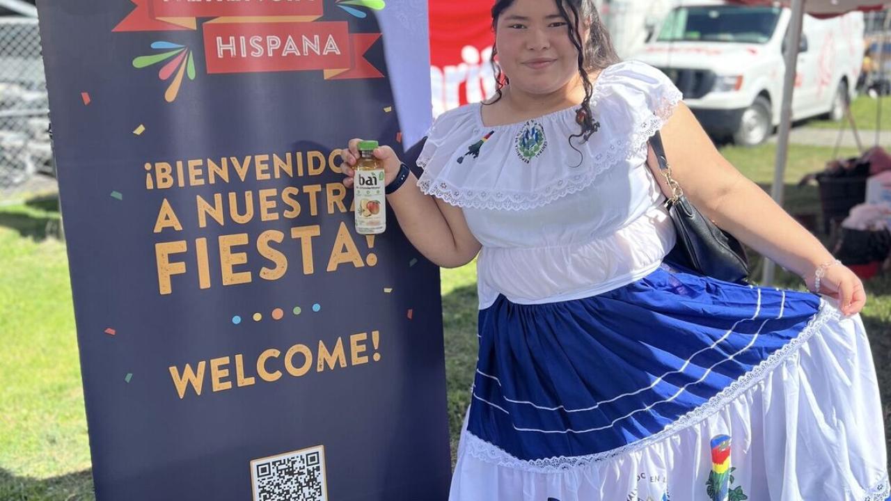 Photo of person dressed in traditional Hispanic clothing in front of Safeway welcome sign displayed in Spanish and English languages