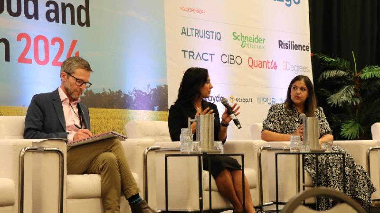 Nivera Wallani and Nira Johri seated on a stage with another.