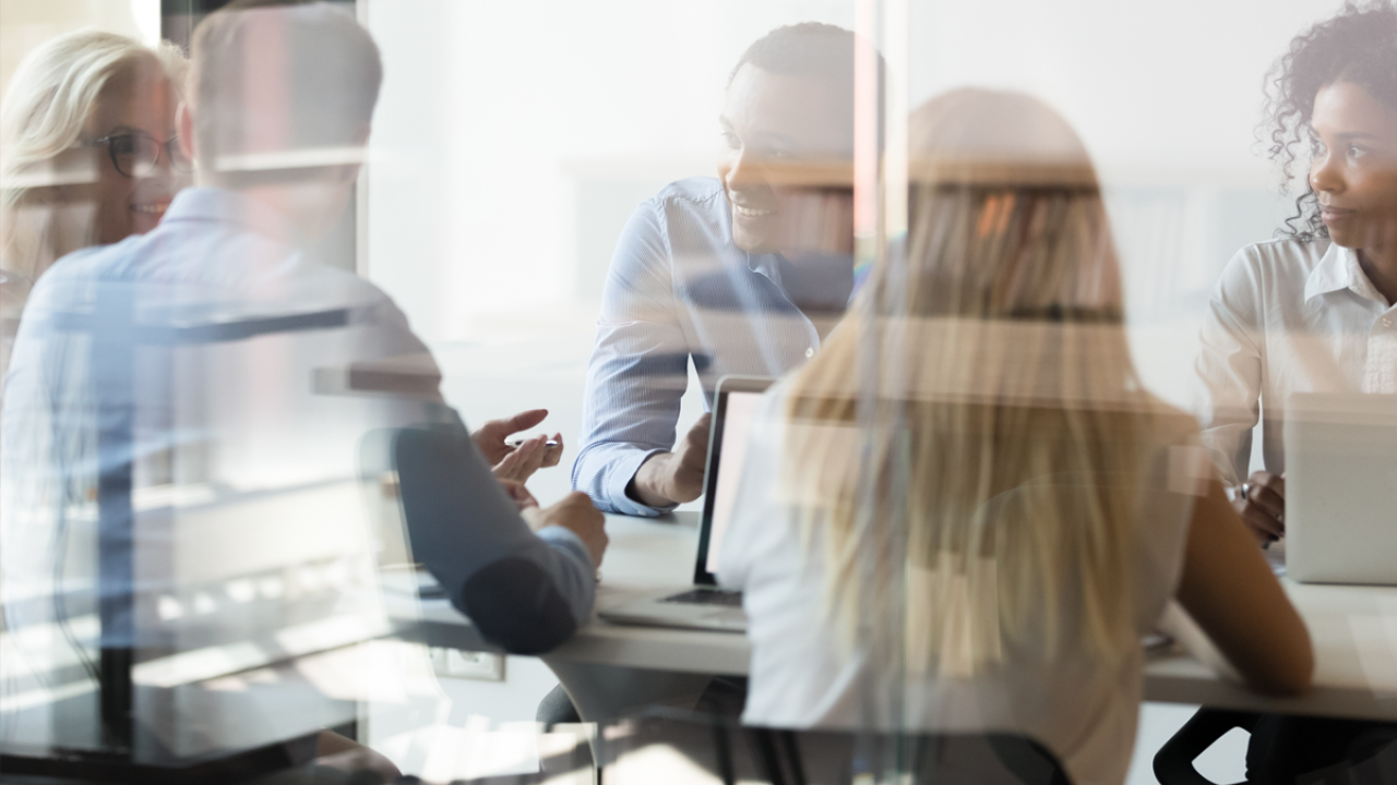 Group working at a conference table, seen through reflective glass