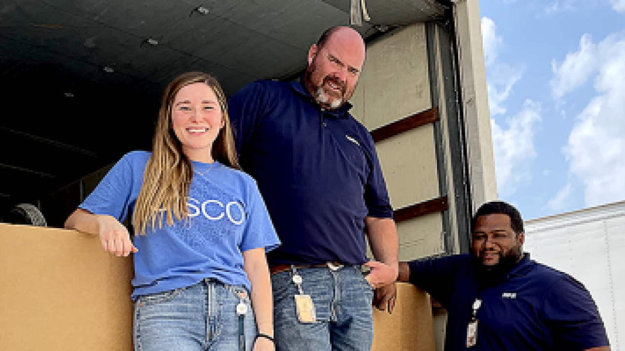 Three Cisco volunteers standing in the back of a box truck