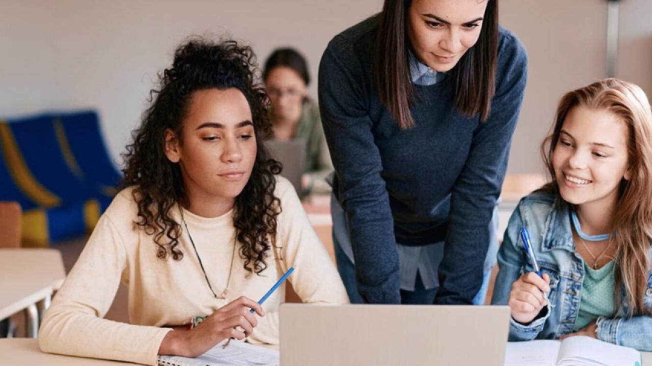 3 women looking at an open laptop