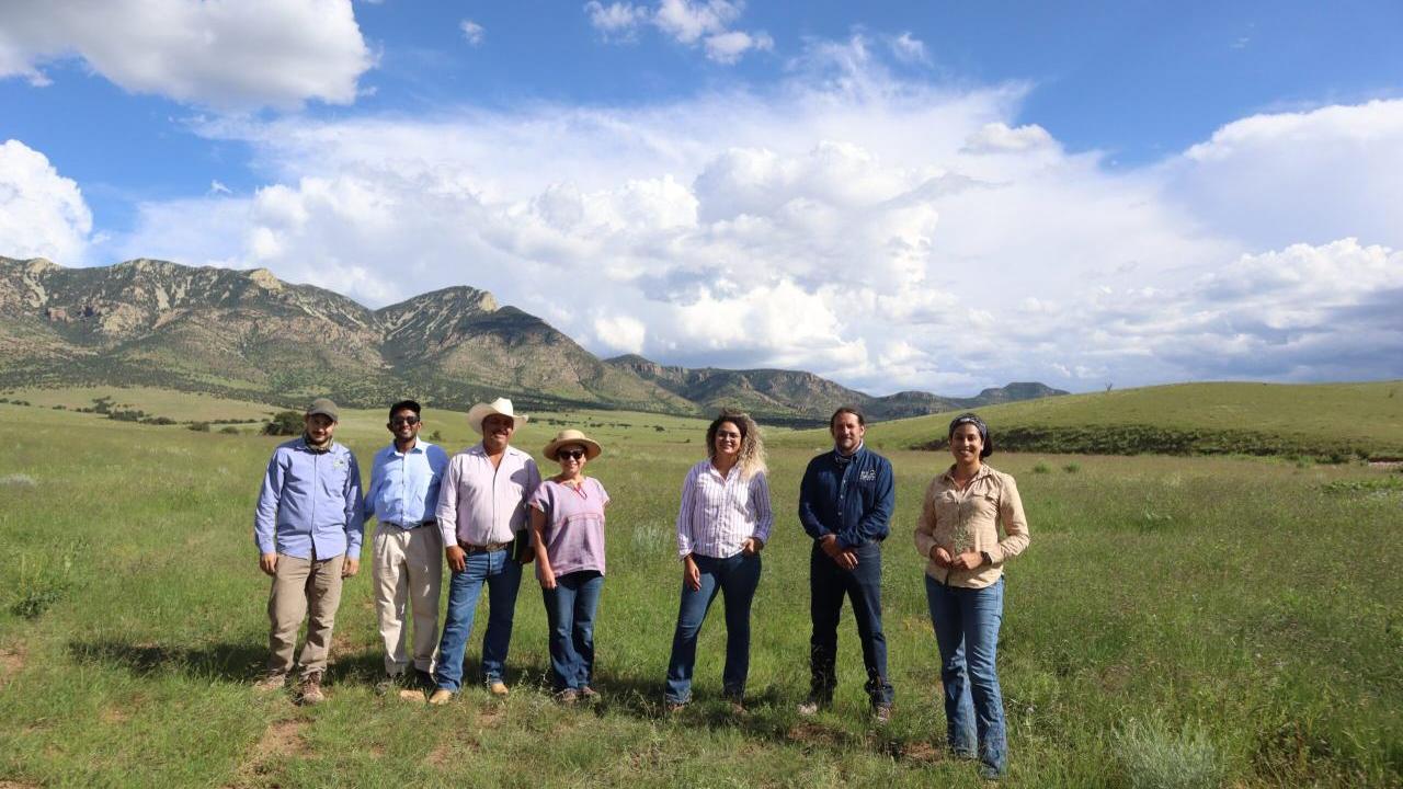 Boomitra staff and stand in a grasslands field with local ranchers 