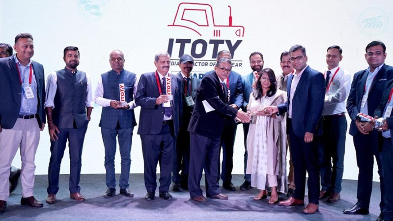 A group of people on a stage, two accepting an award.