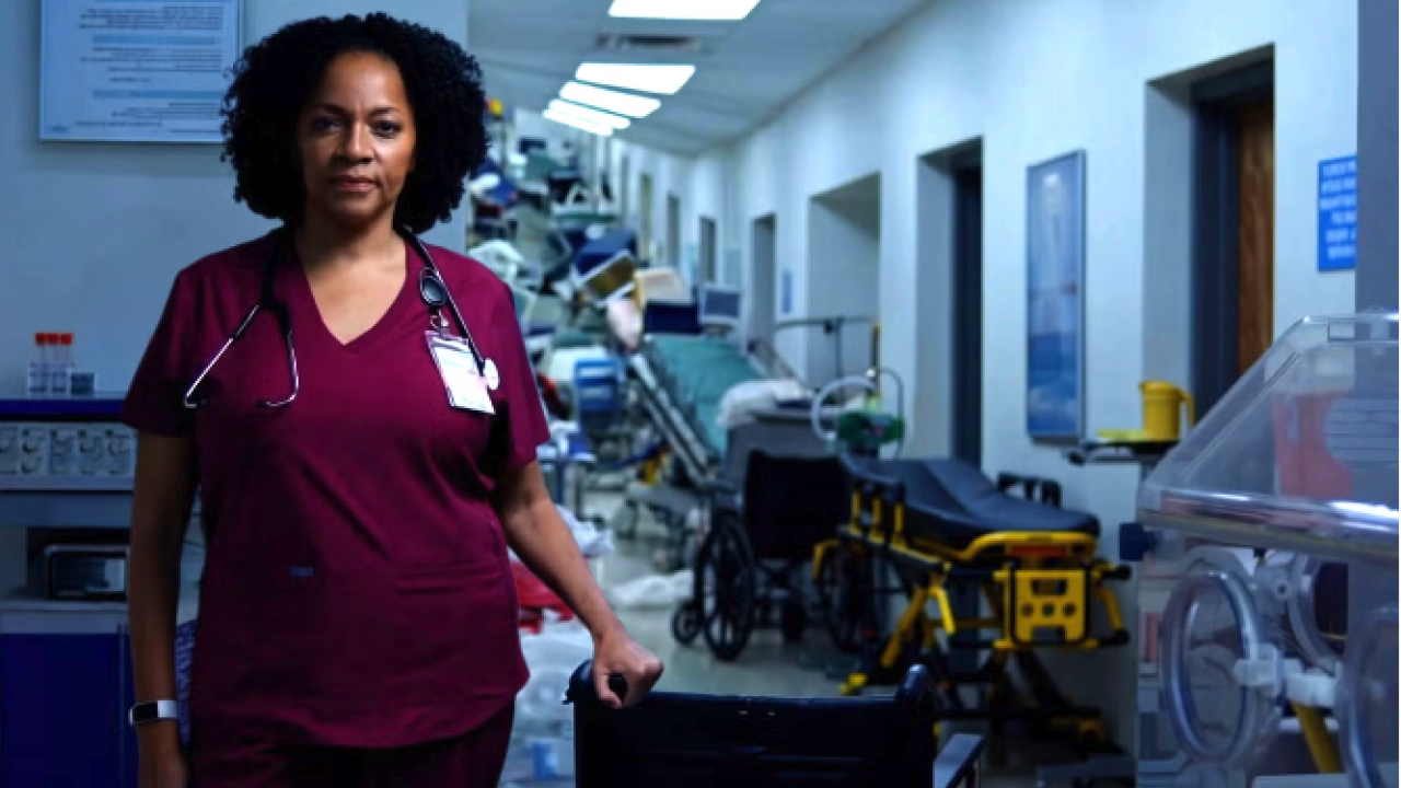 Nurse stands in hallway filled with hospital beds