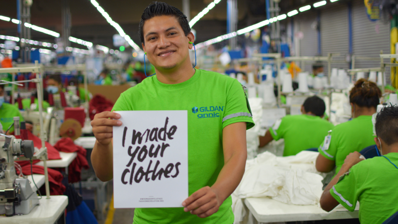 Person holding a sign that says "I made your clothes"