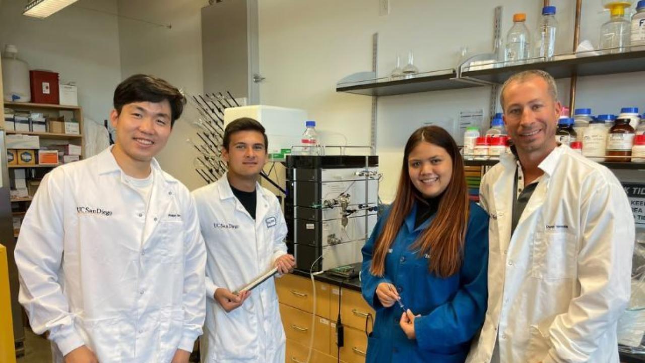 Three students in a lab with a teacher.