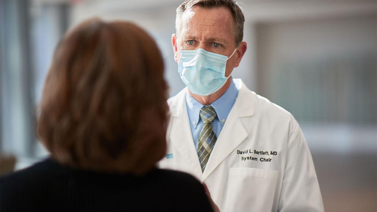 Masked Health Care Professional consulting with a female patient.