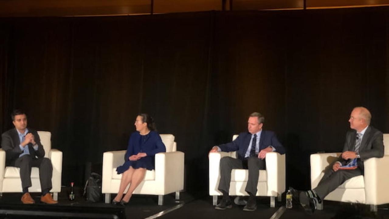 Panel of oncology specialists seated at a conference.