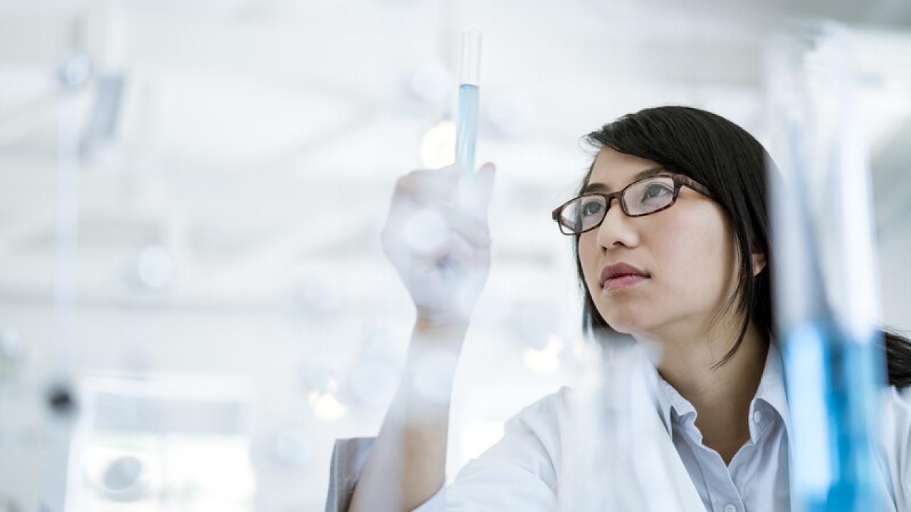 Female scientist in a lab holding a test tube.