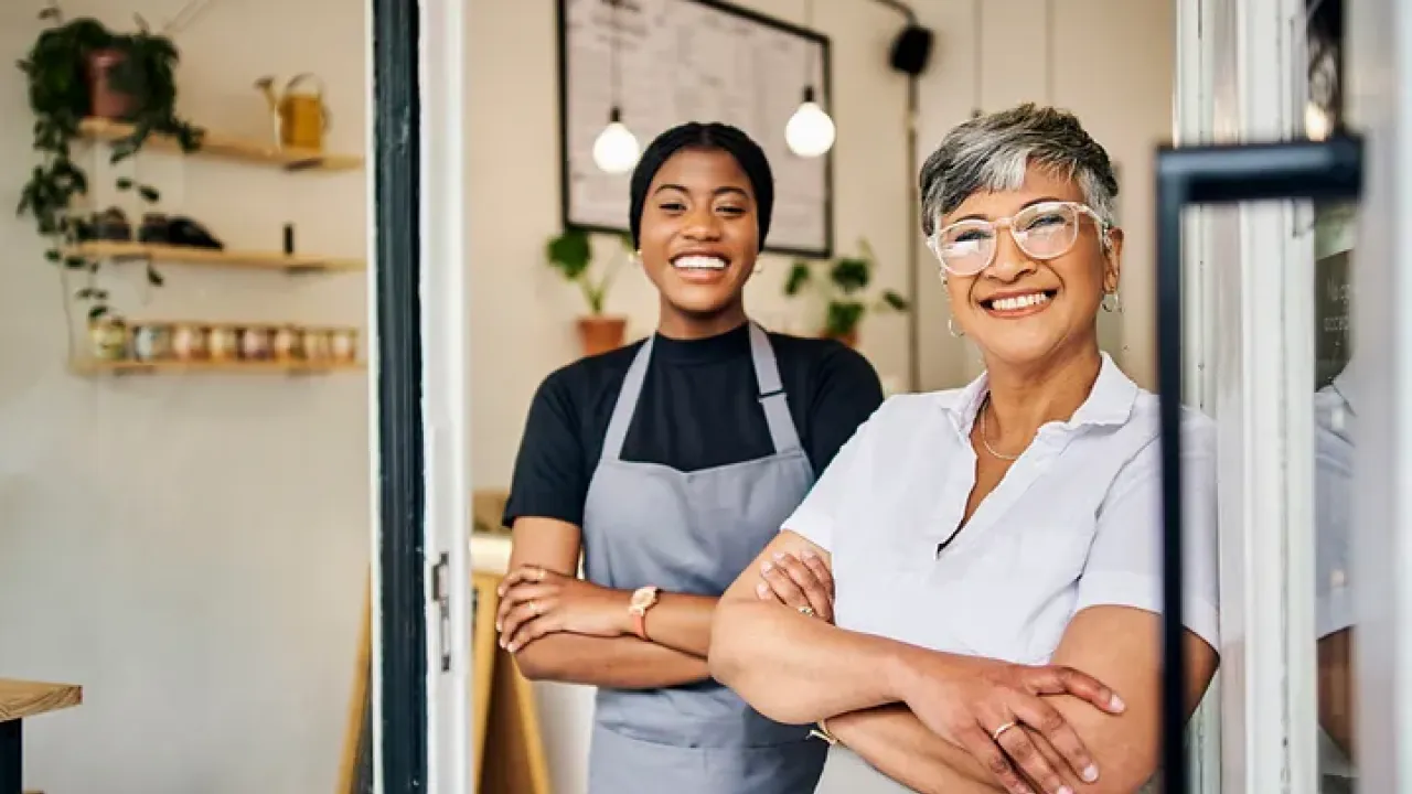 Two people smiling, standing with arms crossed