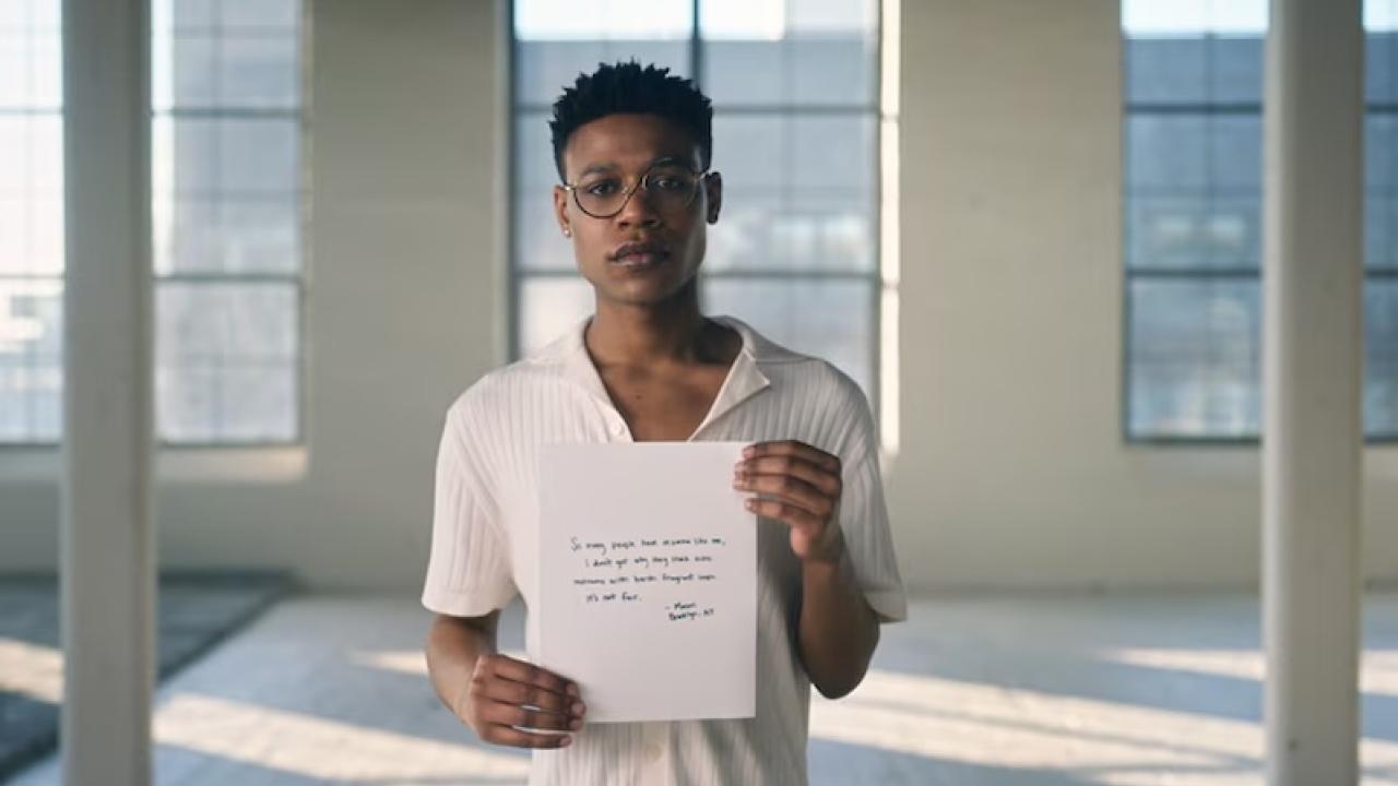 A person standing in a white room holding a sheet of paper.