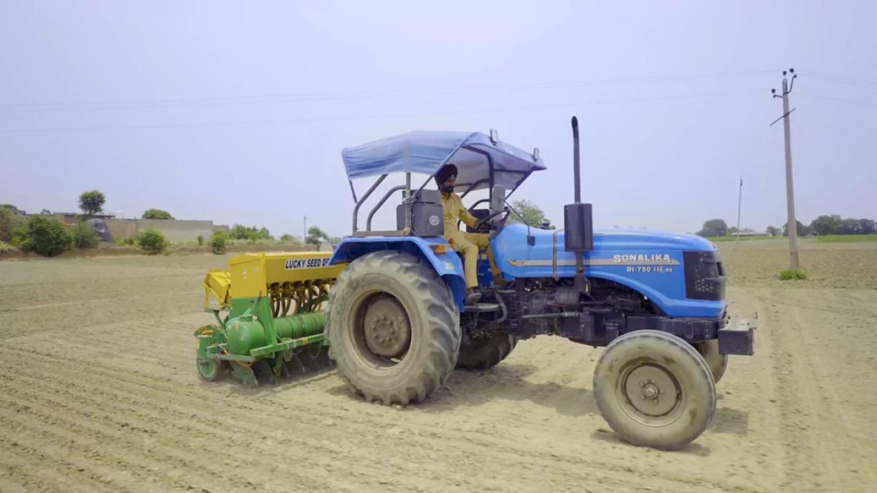 A person in a tractor doing over bare fields.