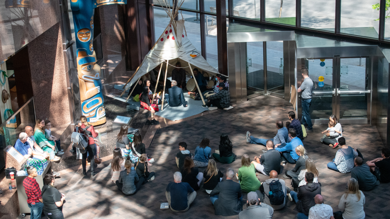 People seated in and around a teepee