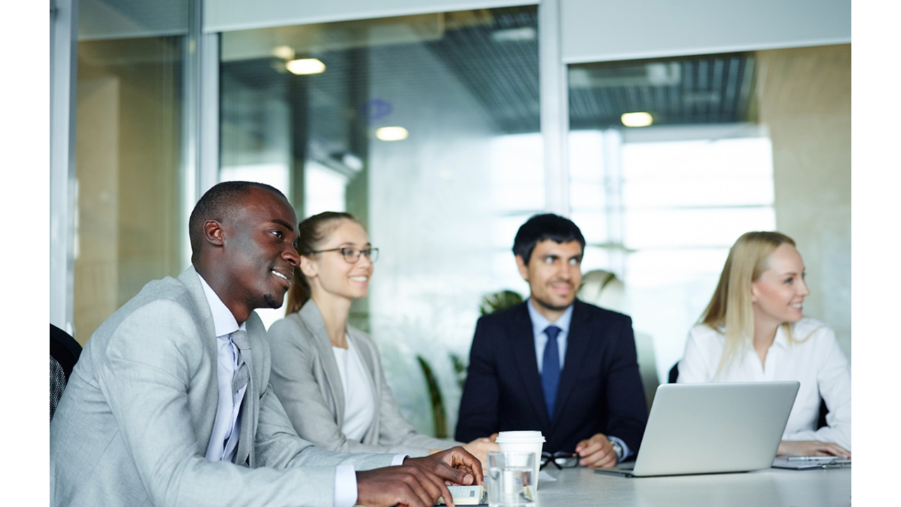 Group of four professionals listening to a presentation in an office