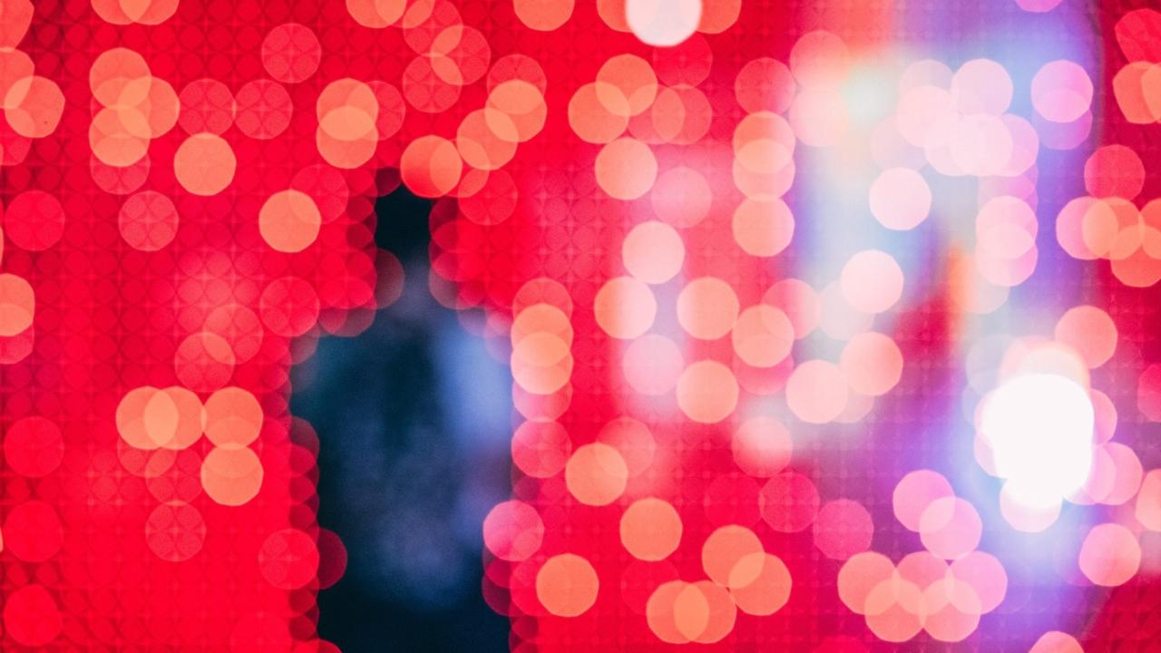 unfocused silhouette of a person in front of a field of pixelated red and blue lights