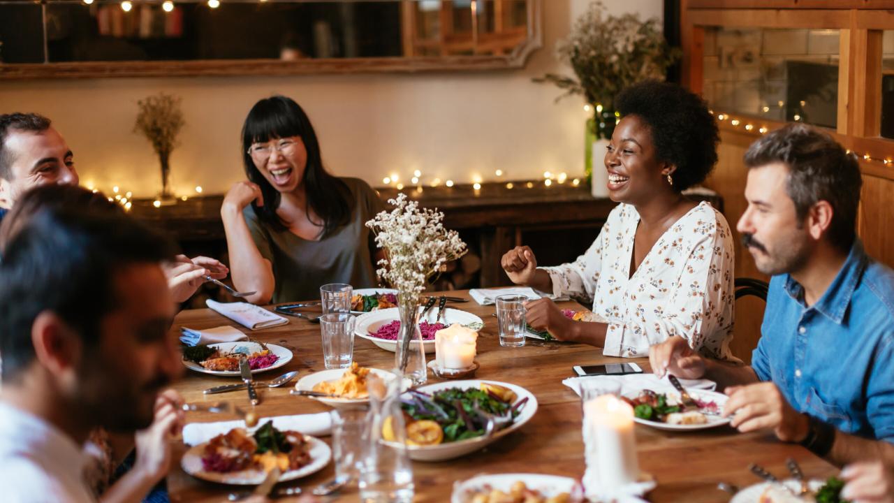 group of people laughing and talking over dinner