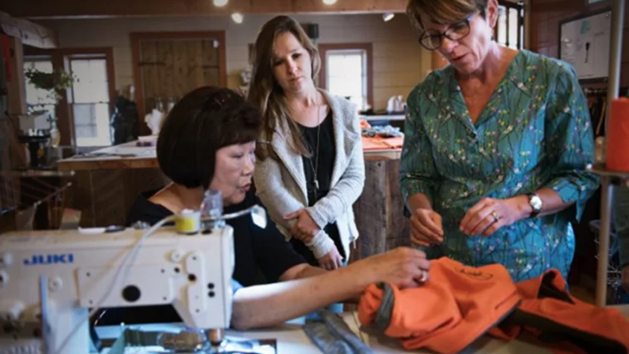 3 people look at a garment being put together