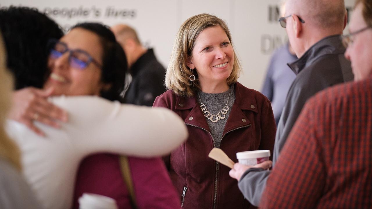 Jennifer Rumsey in a room of people, some hugging, some eating