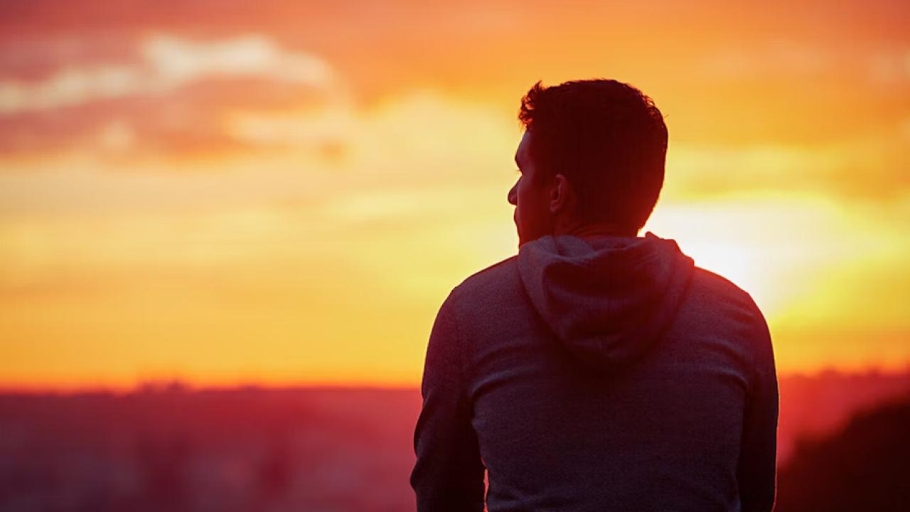 A person looking to the distance, a sunset over the horizon.