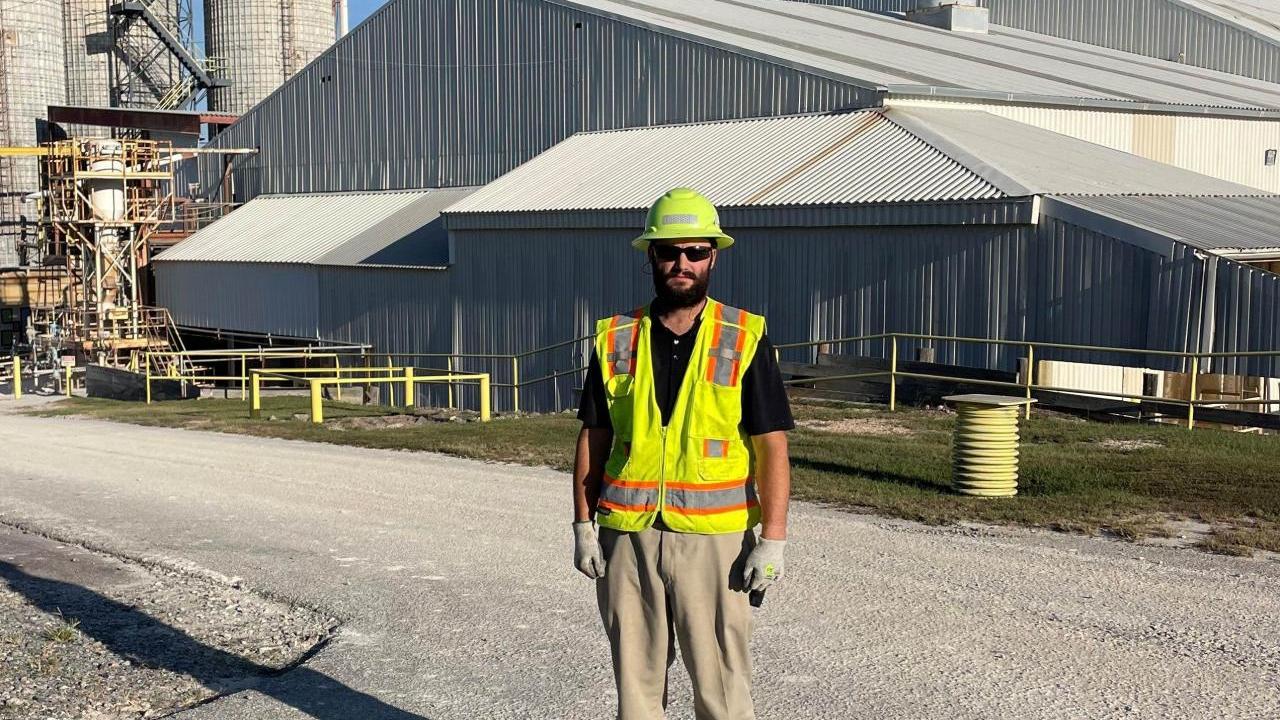John Hargrove standing outside buildings on a driveway in hard hat and high-vis vest.