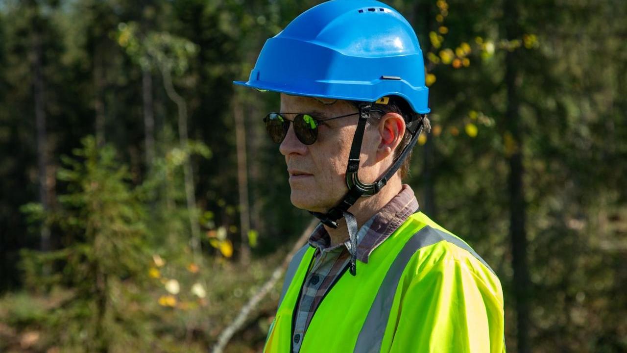 John Mulcahy in hard hat and high-vis clothing standing in a forested area.