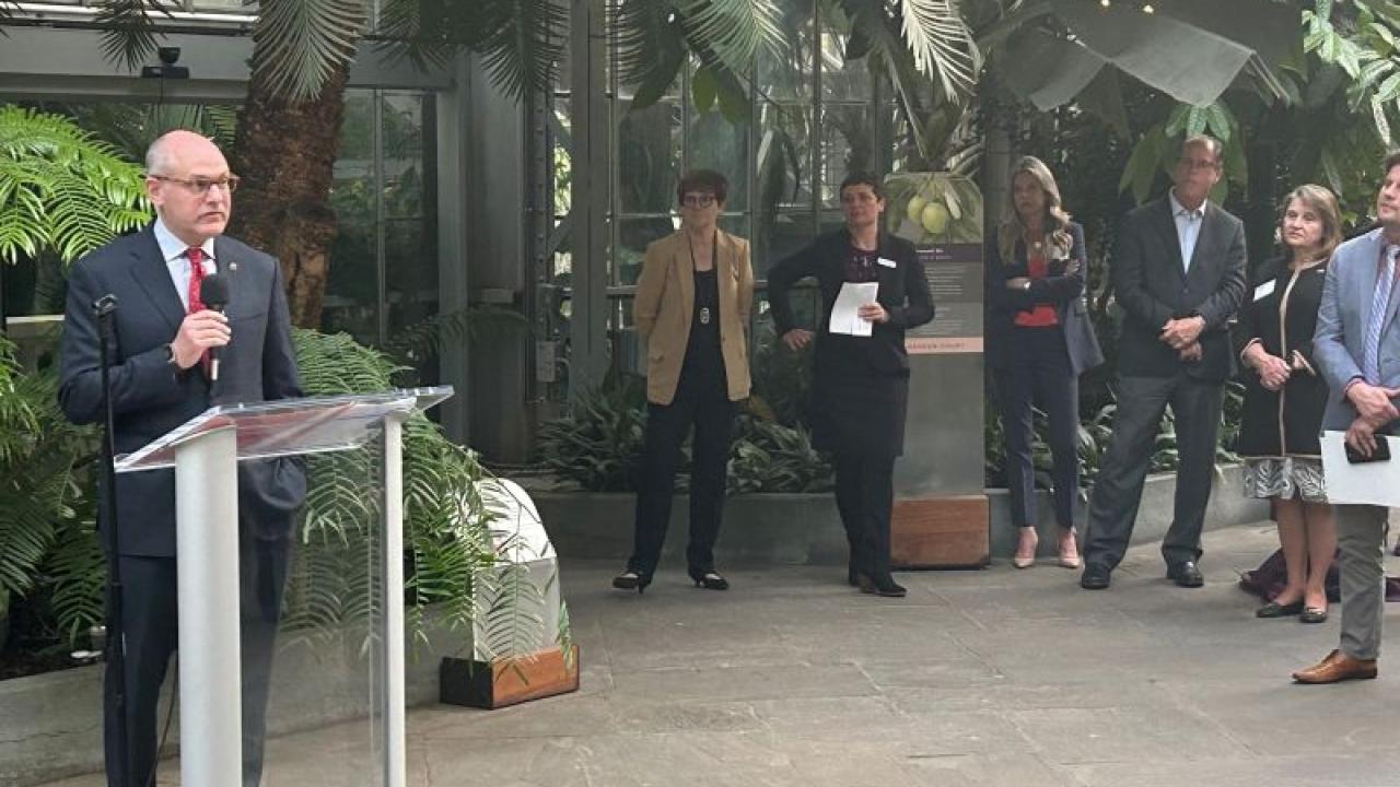 Jon Banner speaking at an outdoor podium.