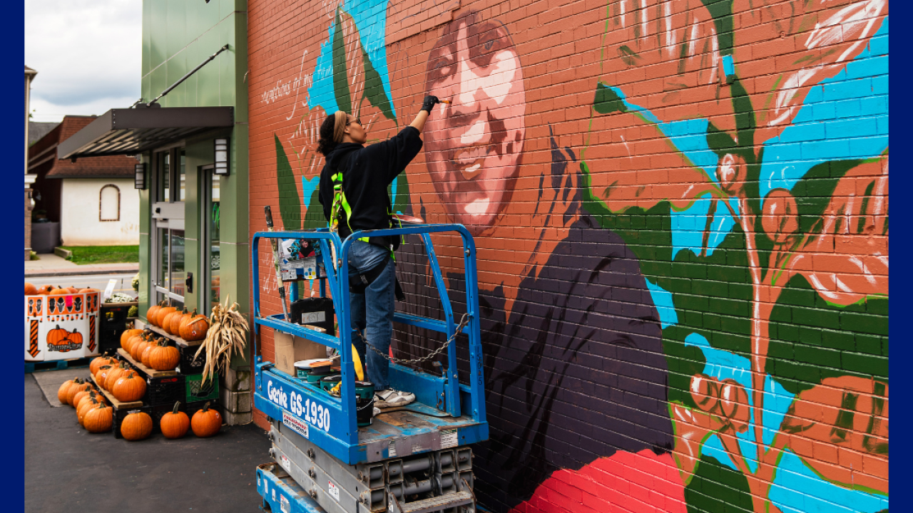 Artist Julia Bottoms paints a mural of Ibu Rahmah, a coffee farmer from Indonesia, outside Lexington Co-Op in Buffalo, NY.