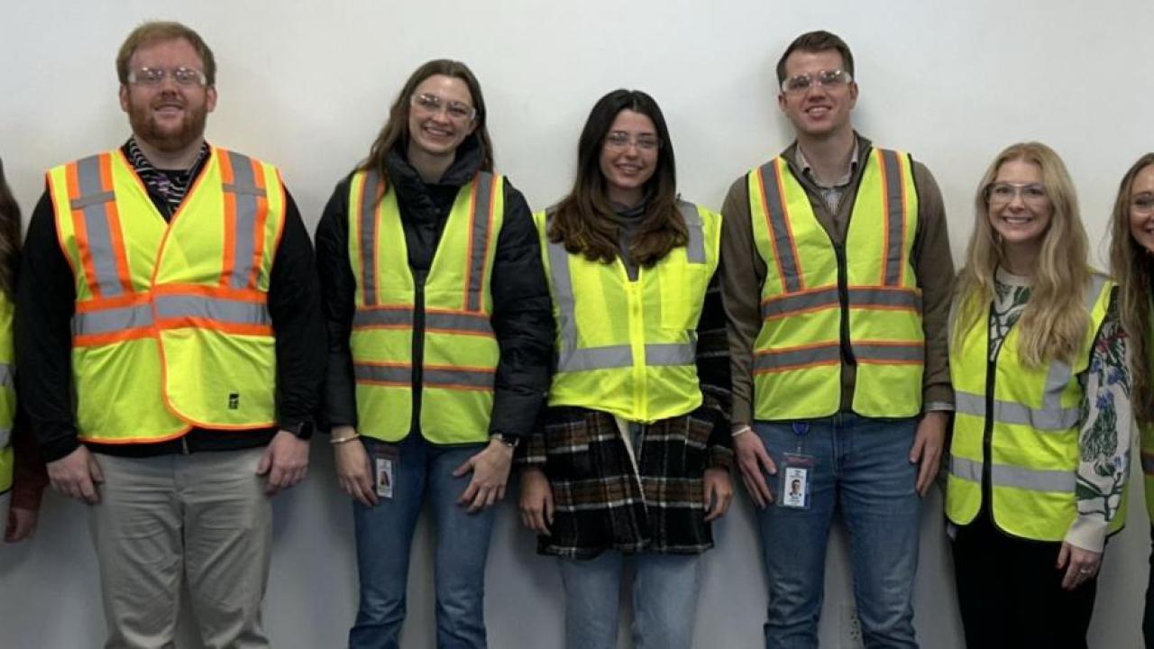 People wearing hi-vis vests while stood in a line against a wall