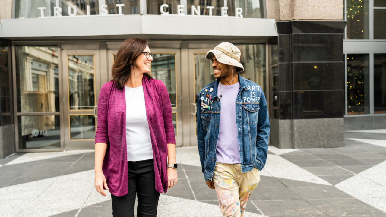Two people walking out of a building smiling at each other