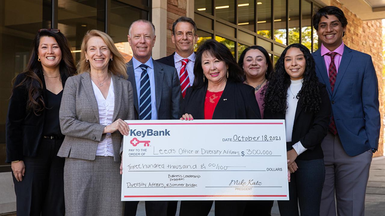 Group of people from Leeds School of Business and KeyBank are holding a check for $300,000. There are 5 women and 3 men in the group.