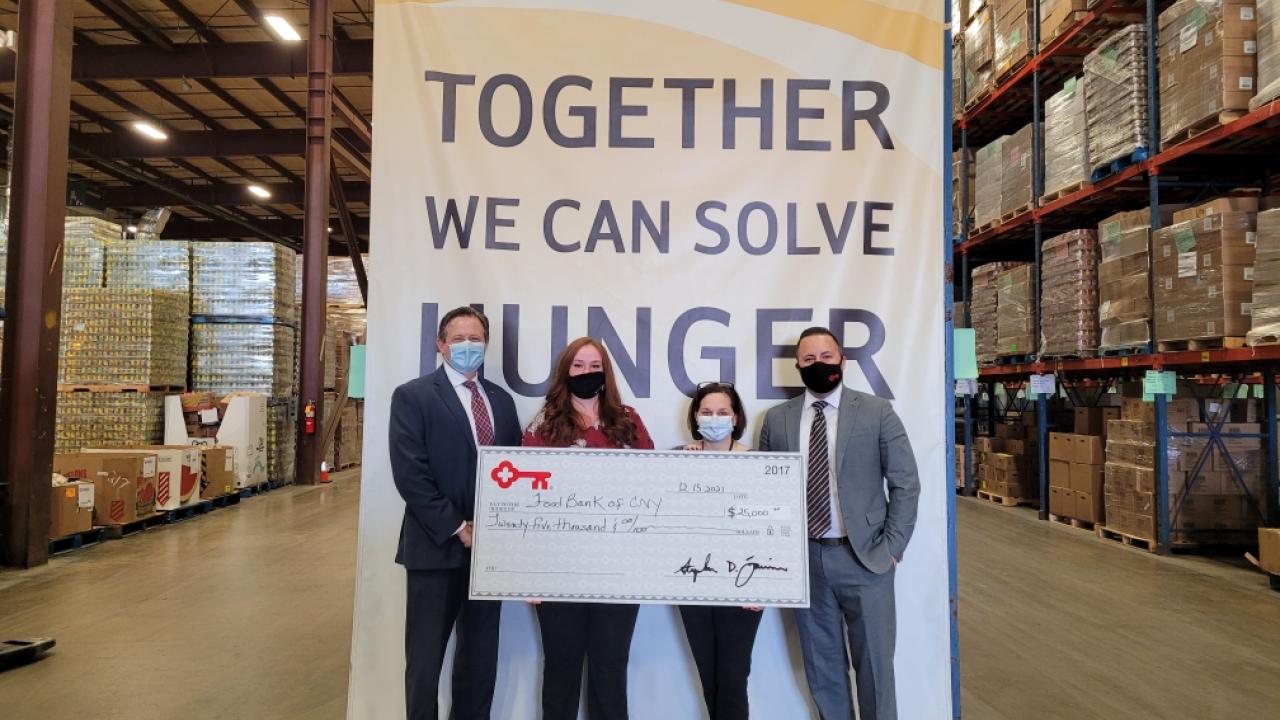 Together we can solve hunger banner; 4 members of KeyBank team (2 women and 2 men) are holding a check for $25,000.