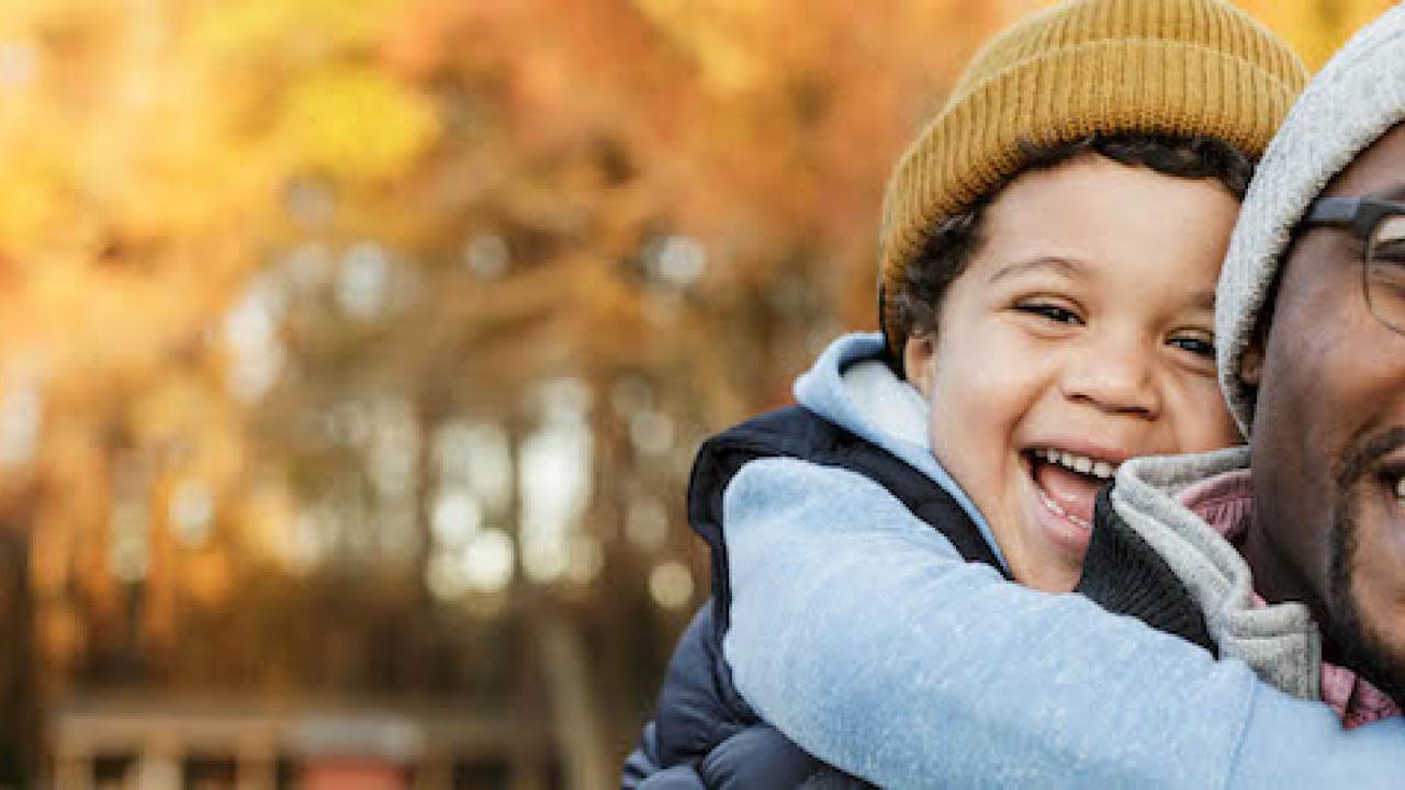 Man pictured with his son in front of a fall foliage scene.