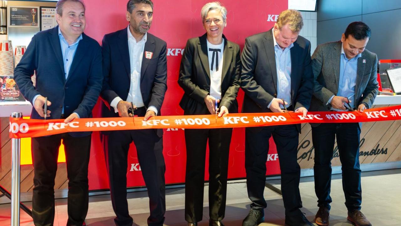 Five people standing behind a ribbon with scissors.