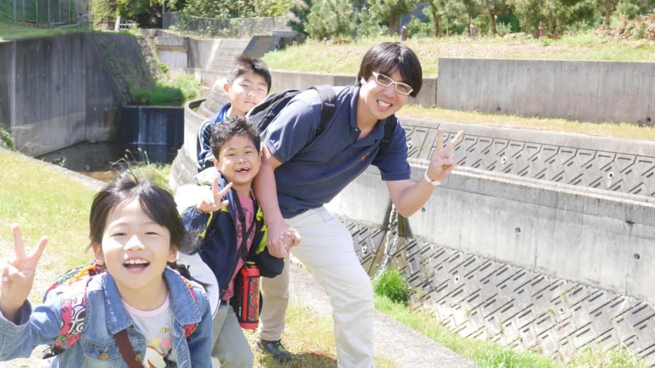 Kobe Jitsugyo Gakuin children and an adult smiling on a field trip