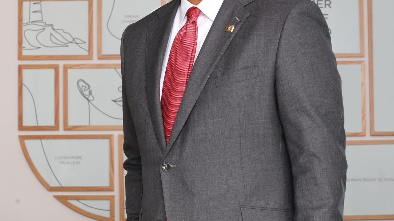 Kala Gibson stood smiling, wearing a grey suit and red tie