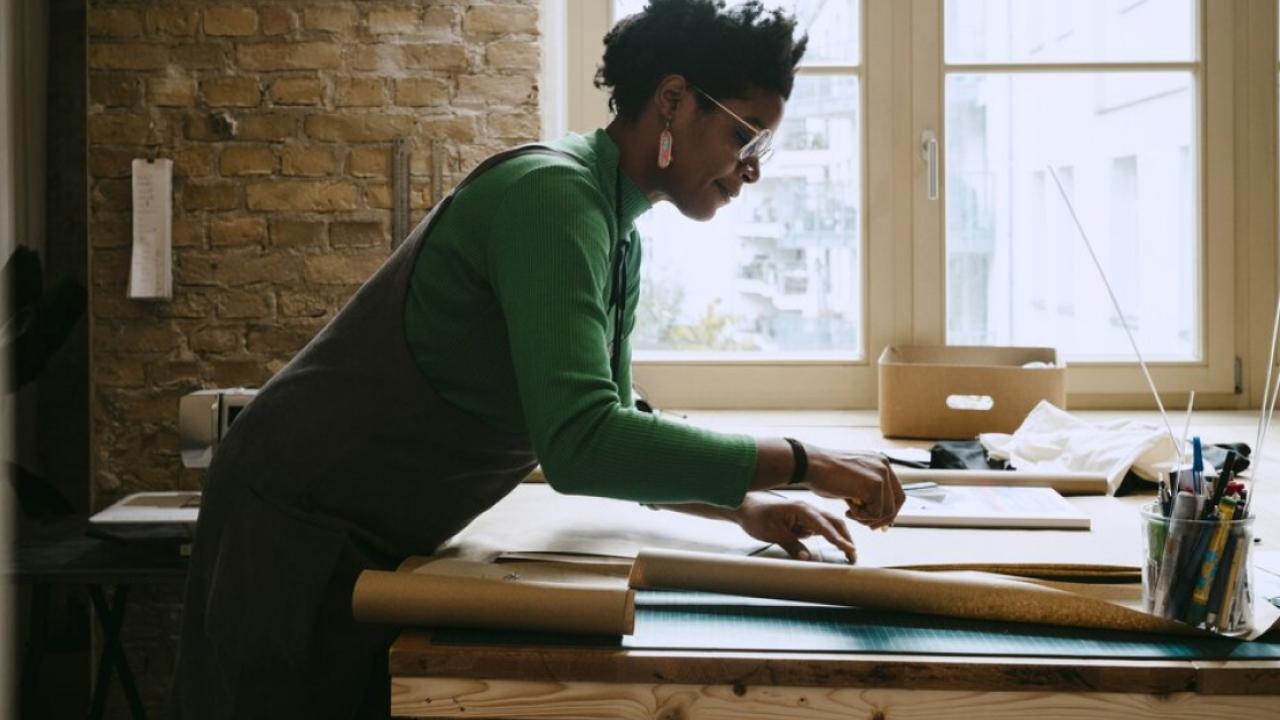 Woman shown standing at a desk reviewing paperwork.
