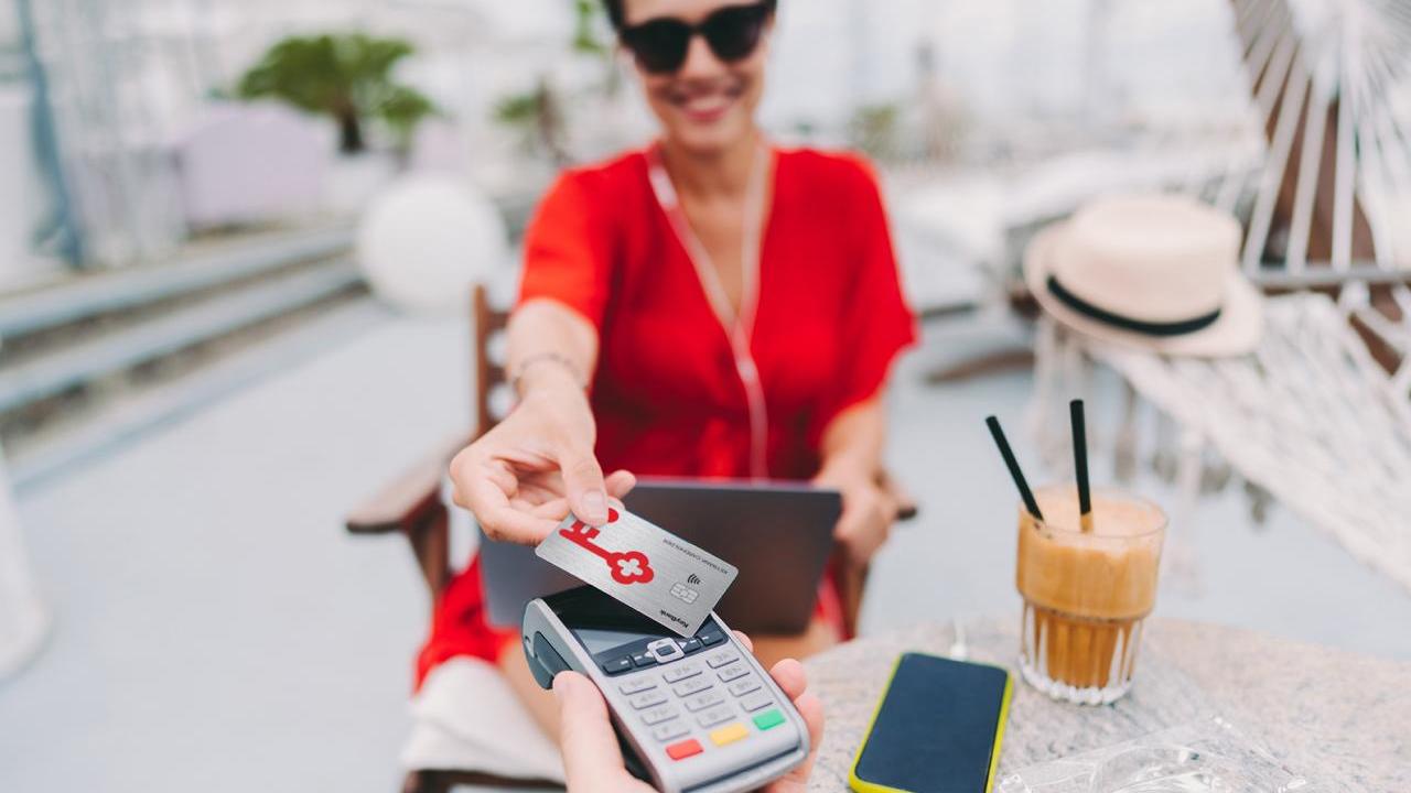 Person at a cafe presenting a KeyBank secured card for payment.