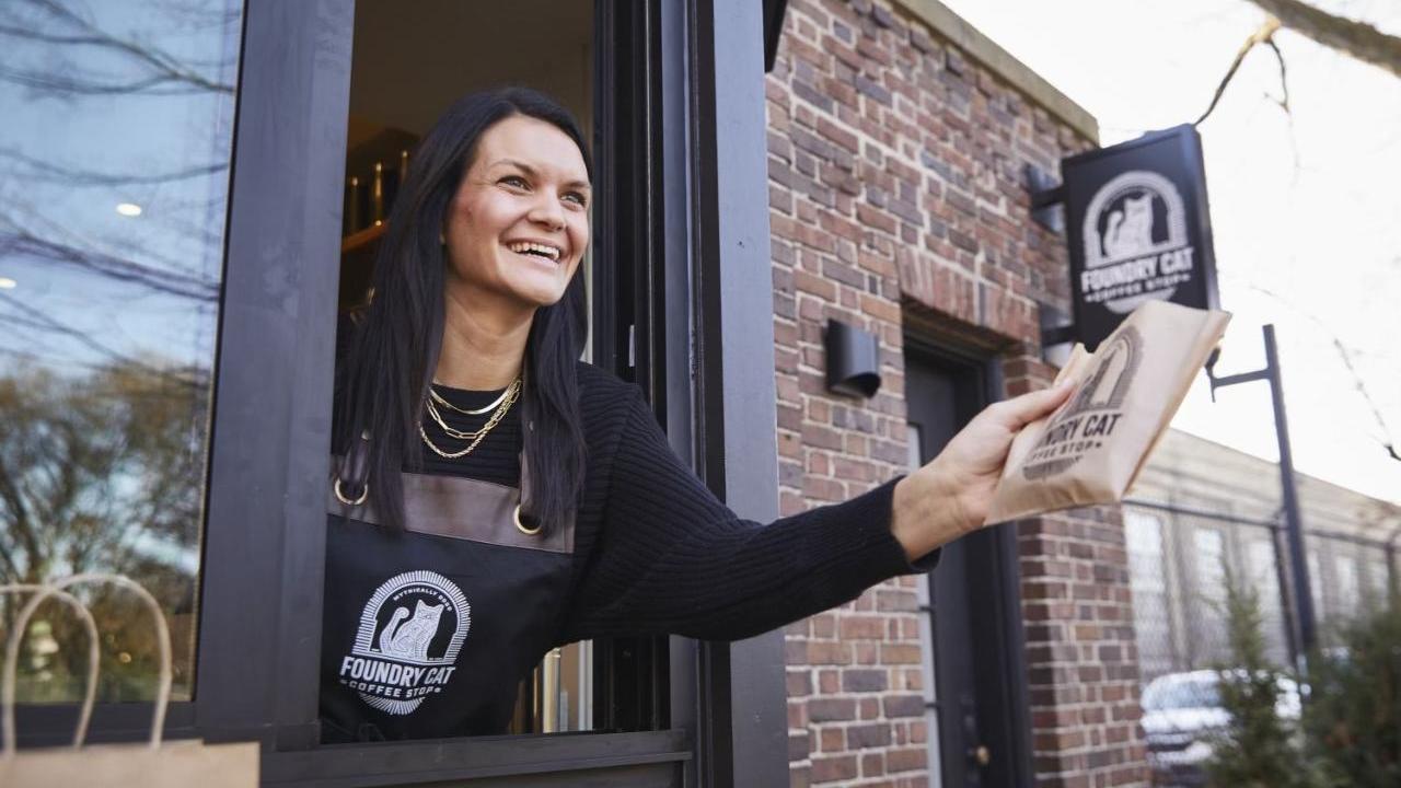 Kimberly Hoffmann leaning out a drive-thru window handing someone an item.