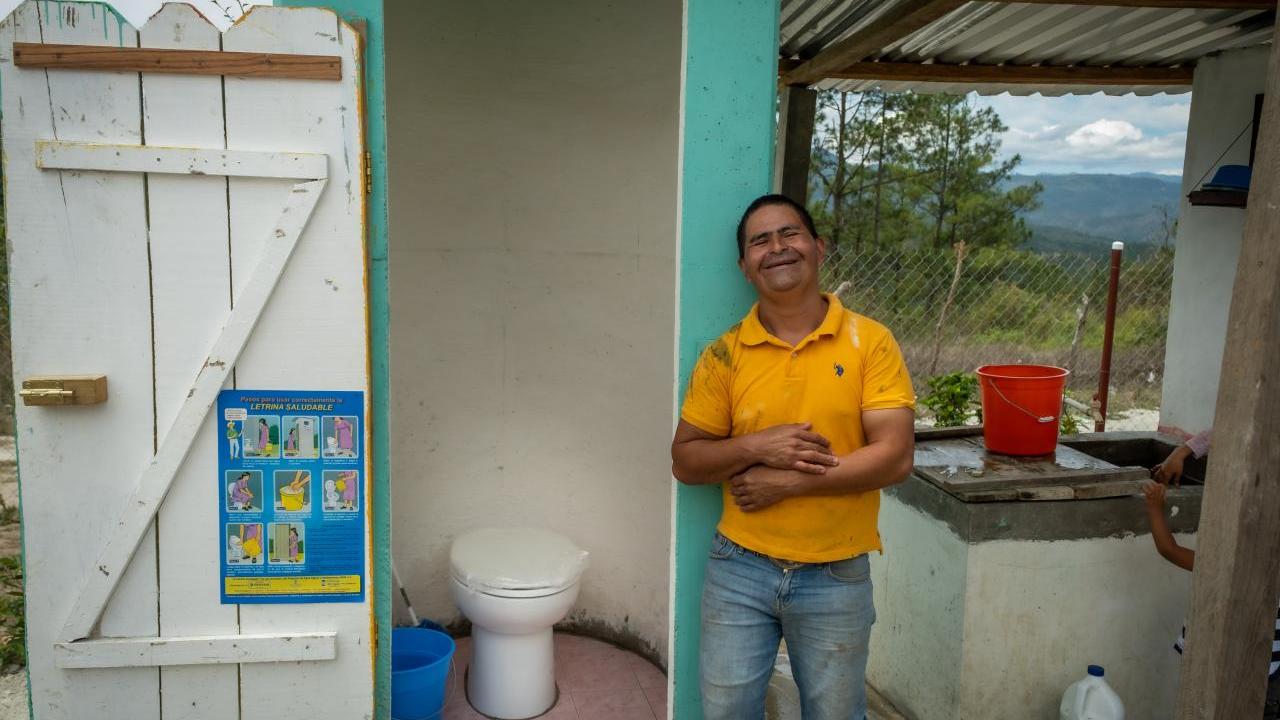 Person smiling next to a new toilet