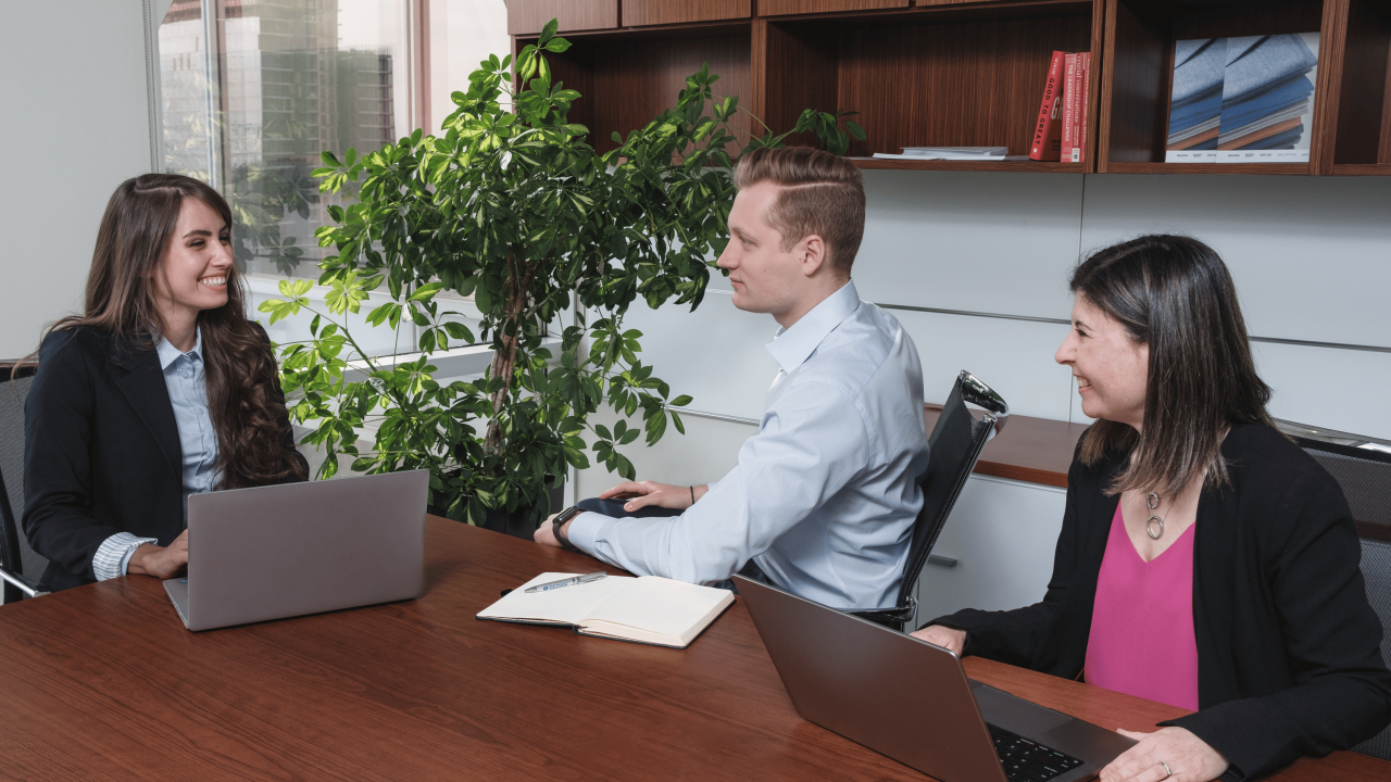 Three Gildan employees sitting around a conference table in an office